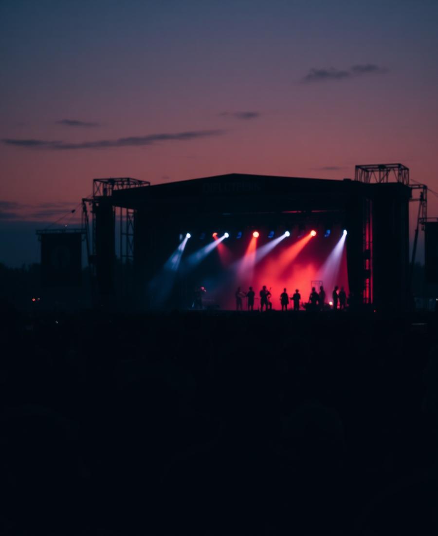 Outdoor festival crowd at dusk lit by warm stage lighting
